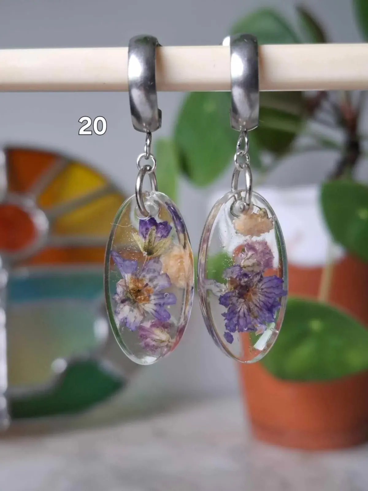 Boucles d'oreilles pendantes ovales en résine transparente avec fleurs séchées violettes suspendues à des créoles