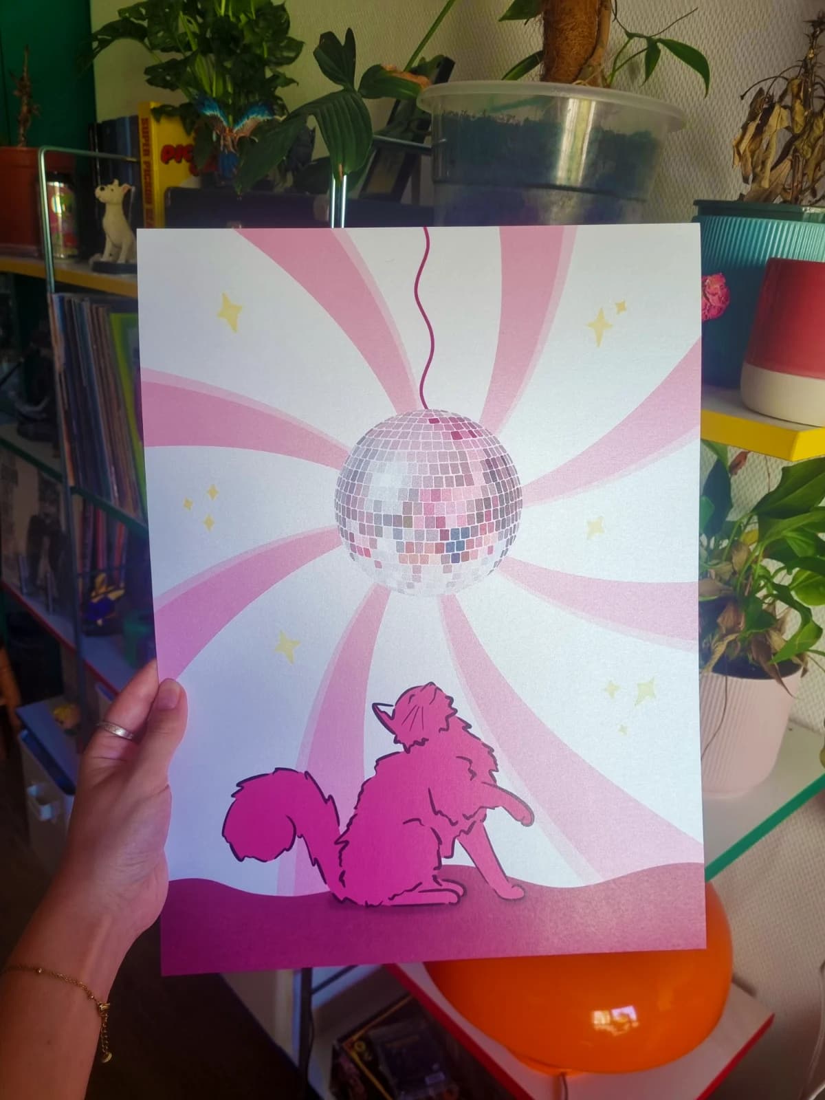 Affiche illustrée d'un chat rose contemplant une boule à facettes sous des rayons spirales roses et blancs.