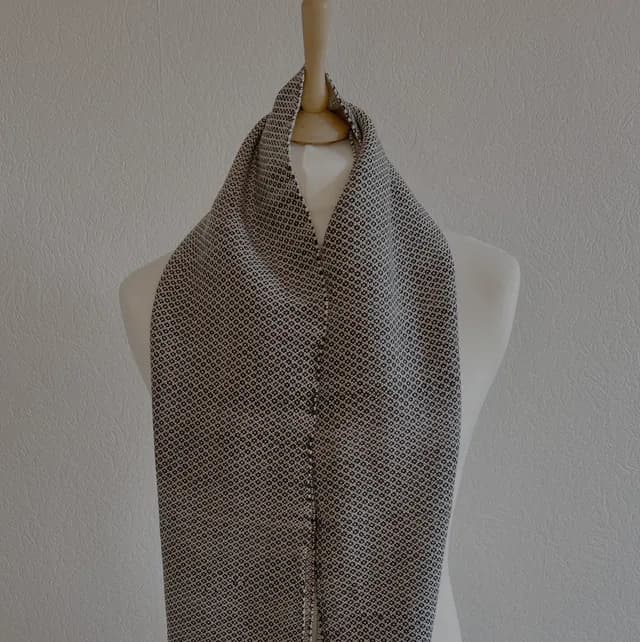 Écharpe tissée noir et blanc en laine mérinos présentée sur un buste mannequin blanc.