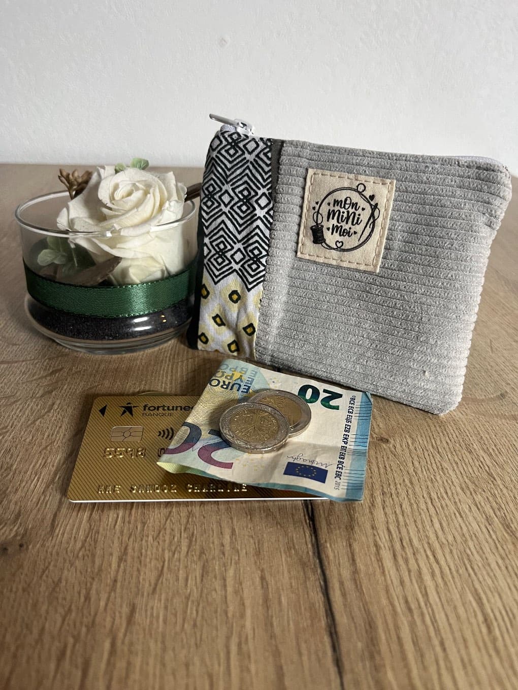 Face avant du porte-monnaie zippé en tissu côtelé gris avec empiècement à motifs géométriques.