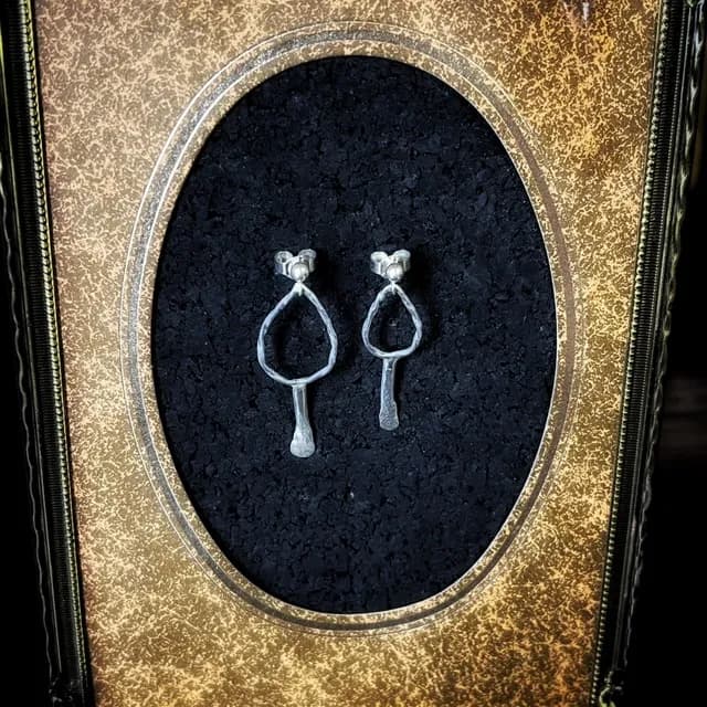 Paire de boucles d'oreilles pendantes en argent 925 aux formes organiques, présentées dans un cadre doré