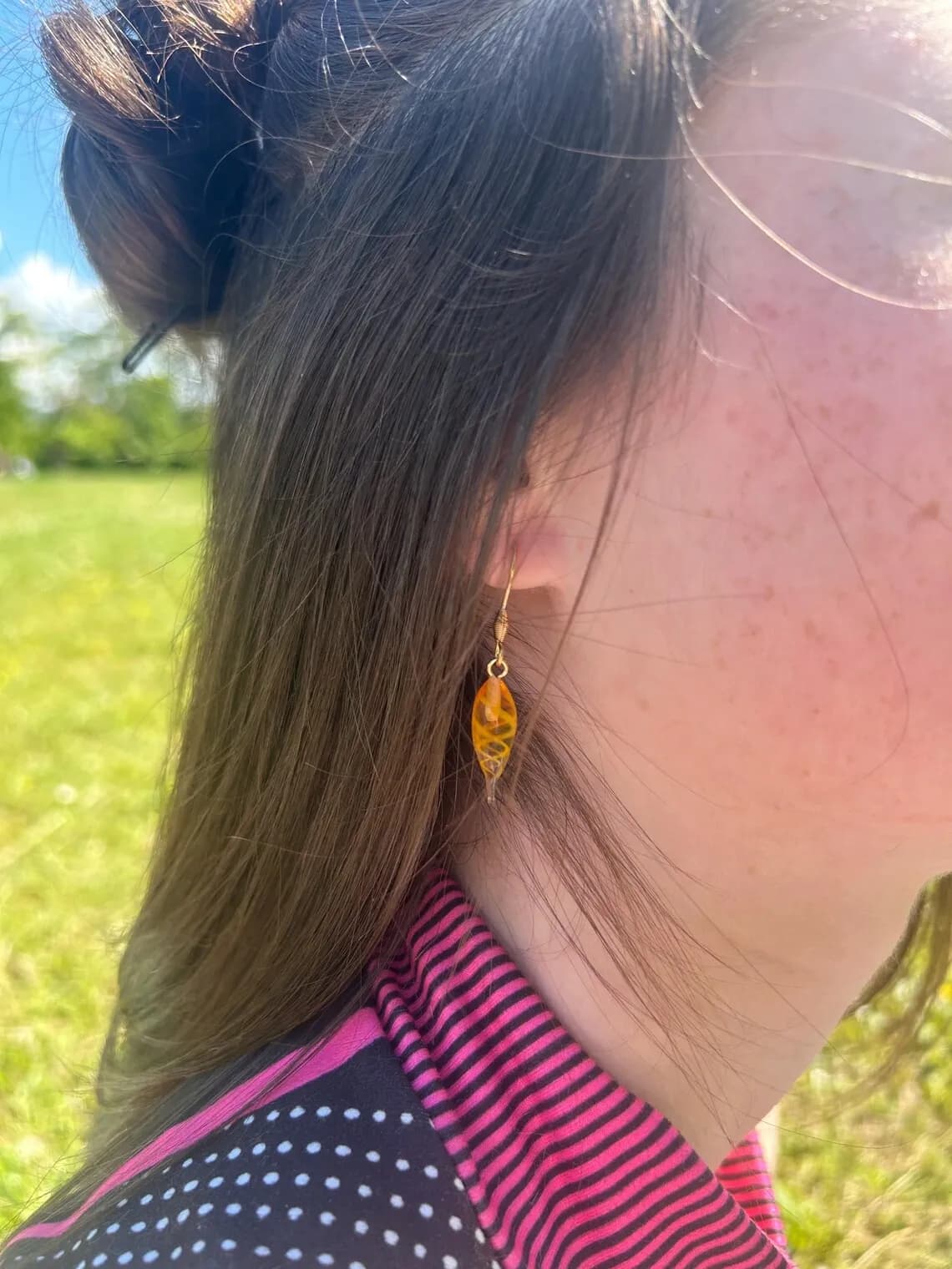 Boucles d'oreilles pendantes orange ambré en forme de goutte sur un présentoir arche face au lac