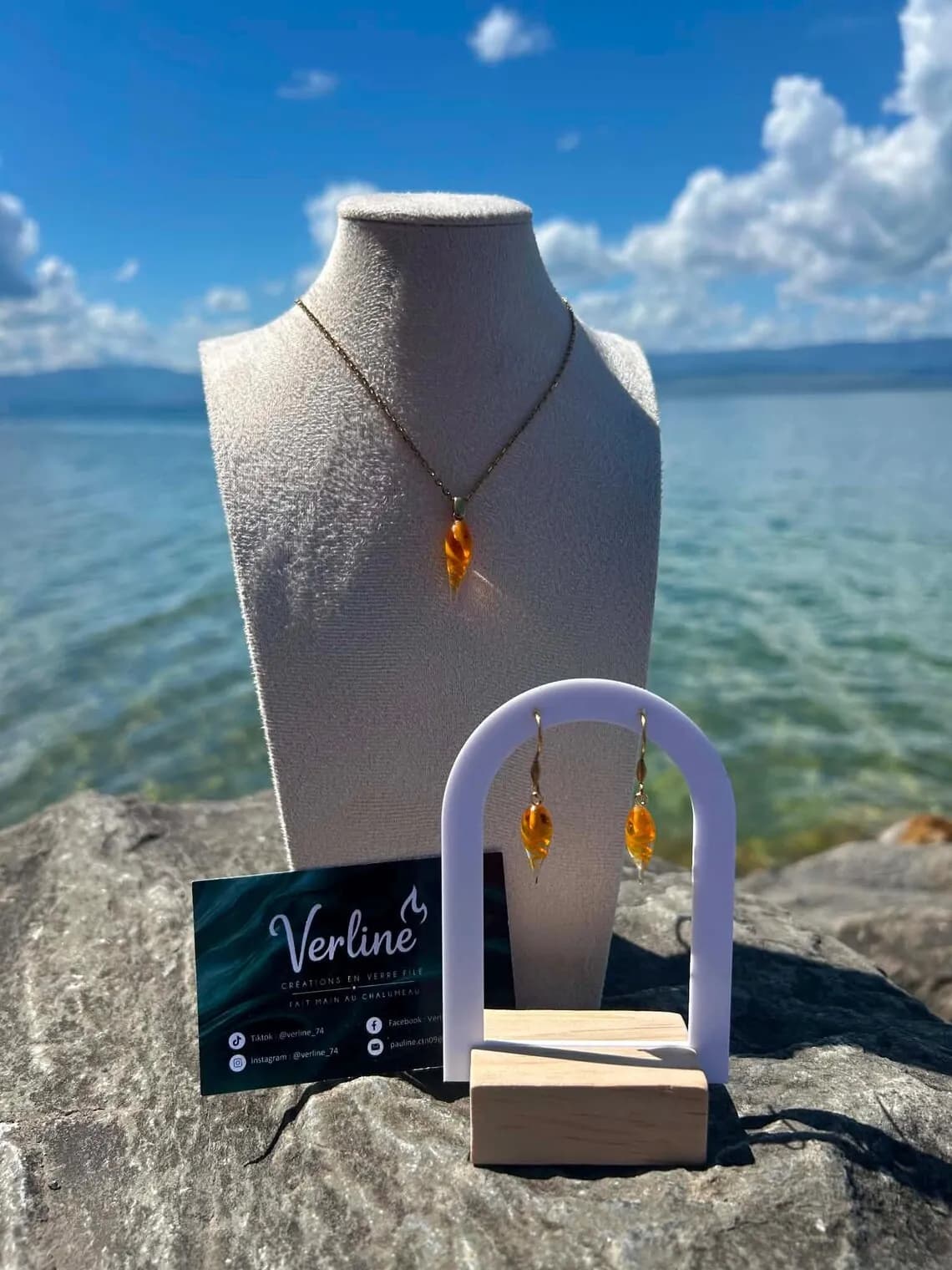 Collier et boucles d'oreilles pendantes en verre filé orange en forme de gouttes sur présentoirs.
